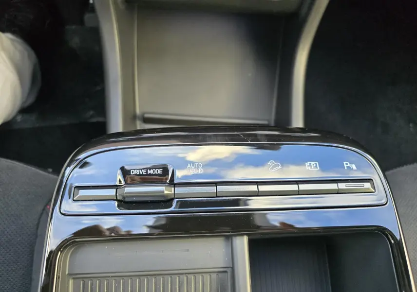 Gros plan sur la console centrale noire brillante du Hyundai Tucson IV N Line avec commandes Drive Mode et Auto Hold visibles.
