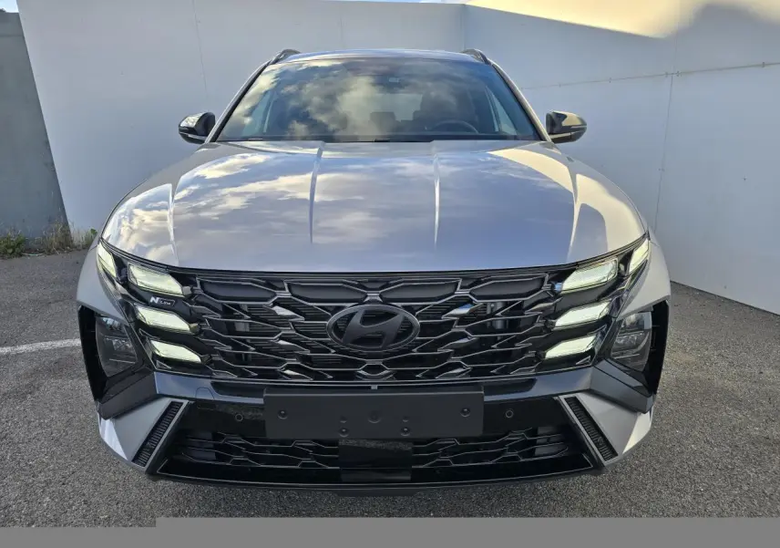 Vue frontale du Hyundai Tucson 2025 en argent métallisé avec calandre noire N Line et feux LED distinctifs.