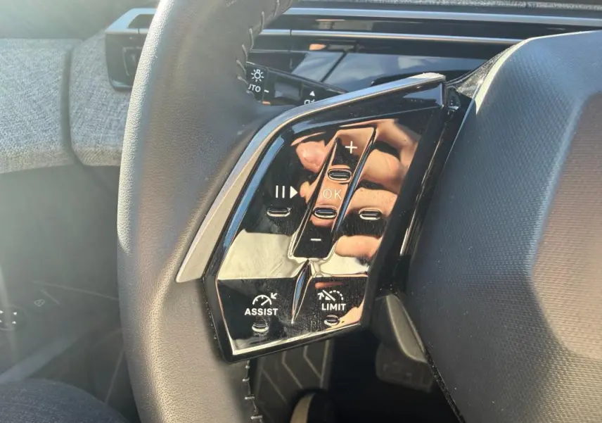 Gros plan sur les commandes gauche du volant du Peugeot 3008 gris 2025 Hybrid Allure avec boutons de régulateur et limiteur.