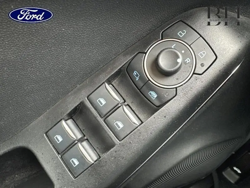 Gros plan sur les commandes de lève-vitres et réglage des rétroviseurs côté conducteur du Ford Puma 2023 en tissu noir.