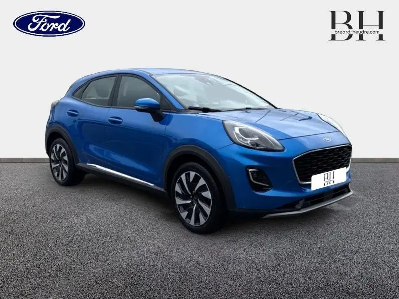 Ford Puma 2023 bleu métallisé en vue 3/4 avant droit, avec calandre noire et jantes bi-ton distinctives.