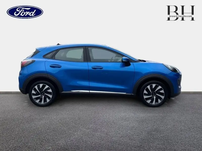 Vue de profil côté gauche d'un Ford Puma 2023 bleu métallisé avec jantes alliage et lignes dynamiques.