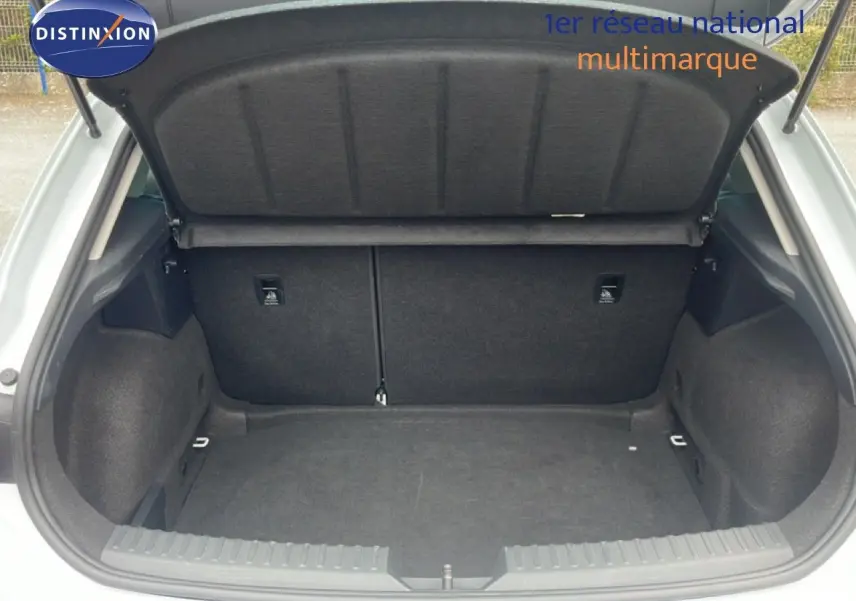 Coffre ouvert vu de l'arrière d'une SEAT LEON blanc neige métal, montrant un espace de chargement propre et spacieux.