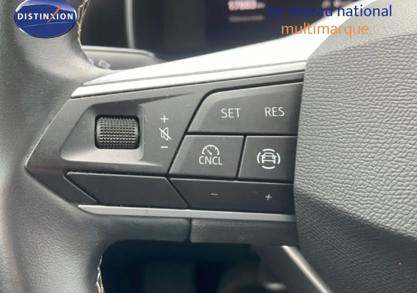 Gros plan sur les commandes au volant à gauche du SEAT LEON blanc neige métal, version 2.0 TDI 115CH STYLE XL 2025.