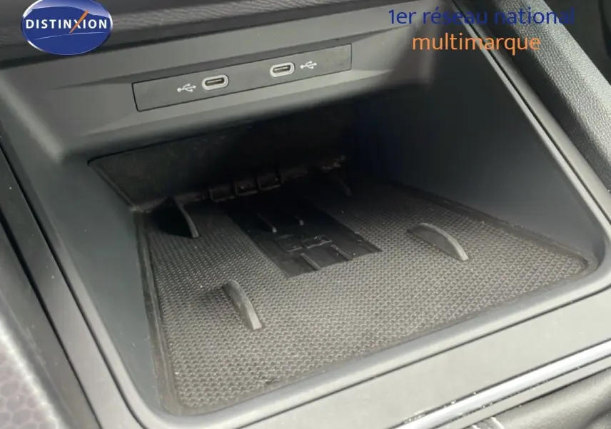 Gros plan sur la console centrale noire avec ports USB et espace de rangement du SEAT Leon blanc neige métal.