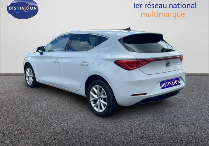 Vue 3/4 arrière droite d'une SEAT Leon blanche neige métal, avec feux arrière LED et jantes alliage.