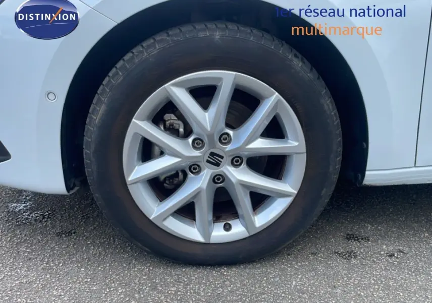 Gros plan sur la roue avant droite d’une SEAT LEON blanc neige métal avec jante alliage à 5 doubles branches.