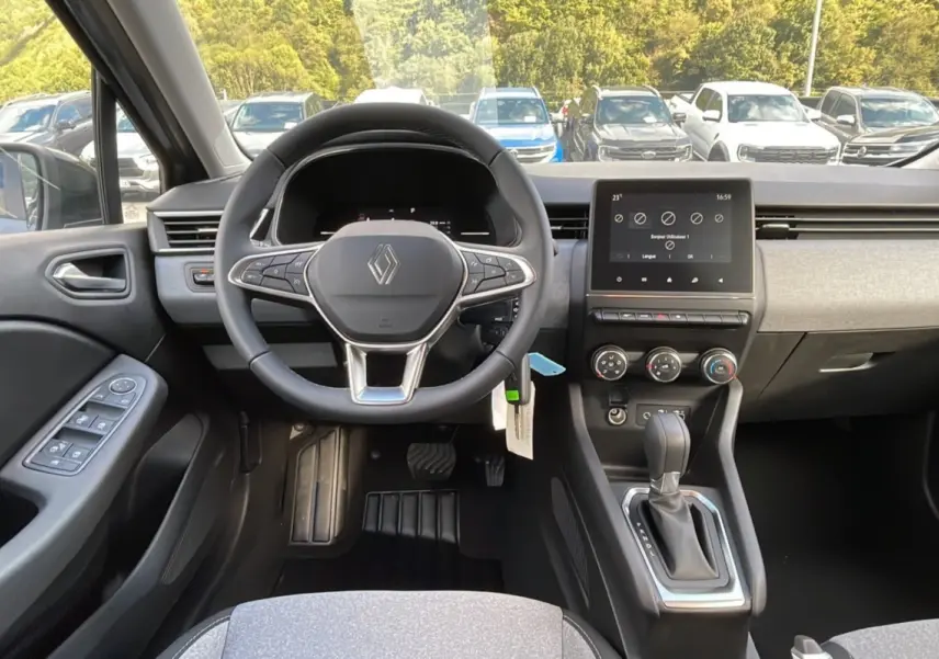 Vue intérieure avant de la Renault Clio 2025, volant multifonctions, écran tactile et levier de boîte auto visibles.
