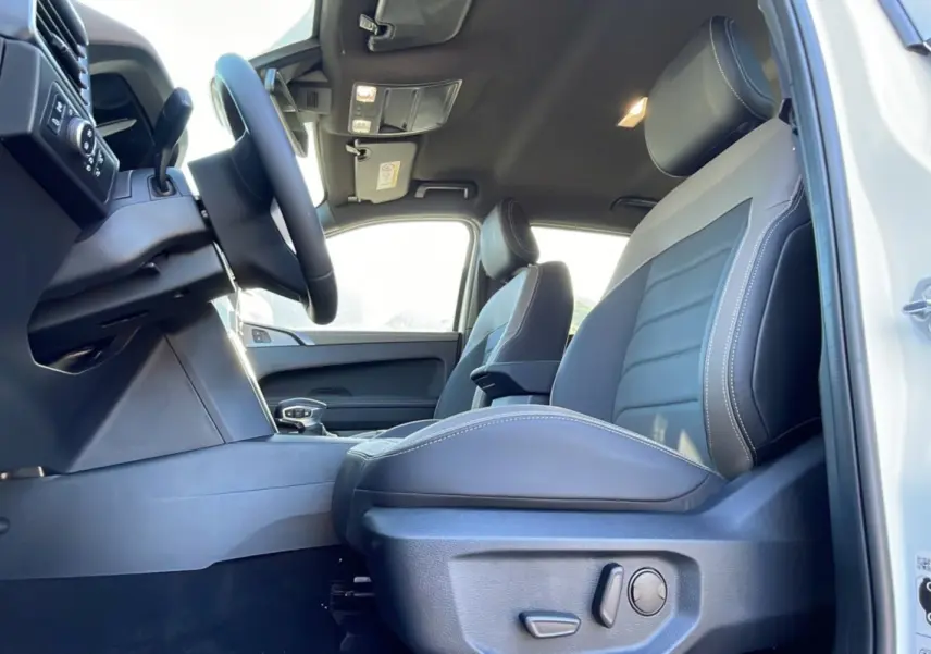 Vue intérieure côté conducteur du Volkswagen Amarok Simple Cabine blanc, sièges cuir gris avec surpiqûres blanches.