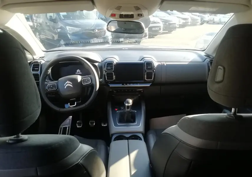 Vue intérieure avant du Citroën C5 Aircross gris, volant multifonction, tableau de bord moderne et levier de vitesse manuel.