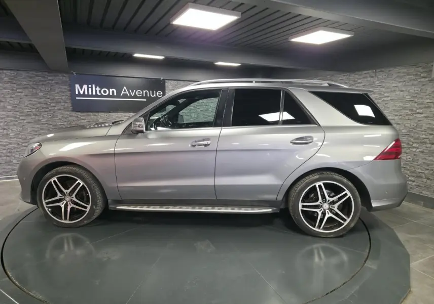 Vue latérale droite d'un Mercedes GLE 350 d gris clair avec jantes AMG 21 pouces et marchepieds inox.