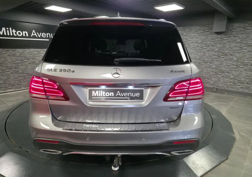 Vue arrière d'un Mercedes GLE 350 d gris clair avec feux allumés et attelage démontable visible.