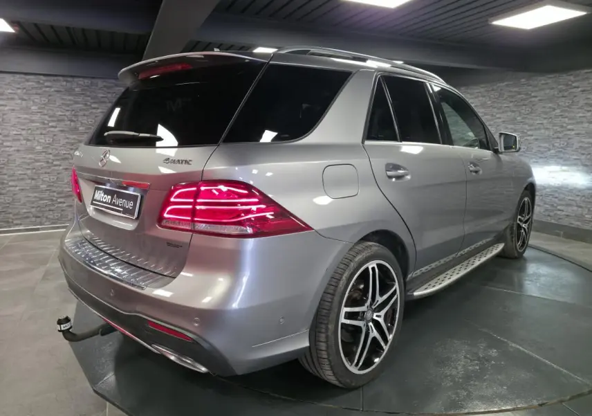 Vue 3/4 arrière droite d’un Mercedes GLE 350 d gris clair avec jantes AMG 21 pouces et attelage démontable.