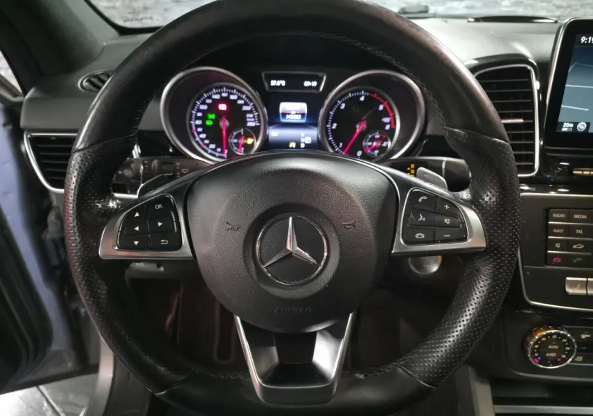 Vue intérieure centrée sur le volant cuir perforé Mercedes du GLE 350 d avec tableau de bord et commandes visibles.