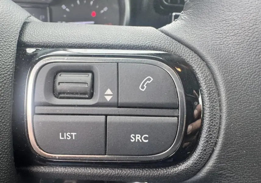Gros plan sur les commandes audio au volant noir du Citroën C3 Aircross 2024 finition Gris Acier.