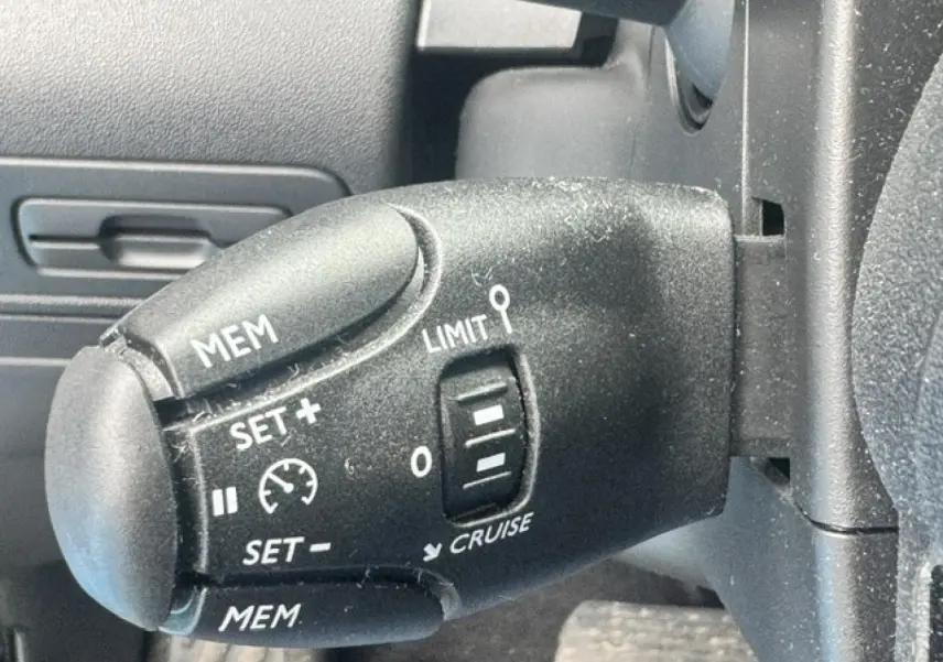 Gros plan sur la commande de régulateur de vitesse côté gauche du volant du Citroën C3 Aircross gris acier.