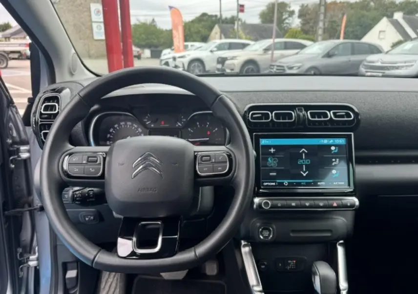 Vue intérieure centrée sur le volant cuir et l’écran tactile du tableau de bord du Citroën C3 Aircross gris acier 2024.