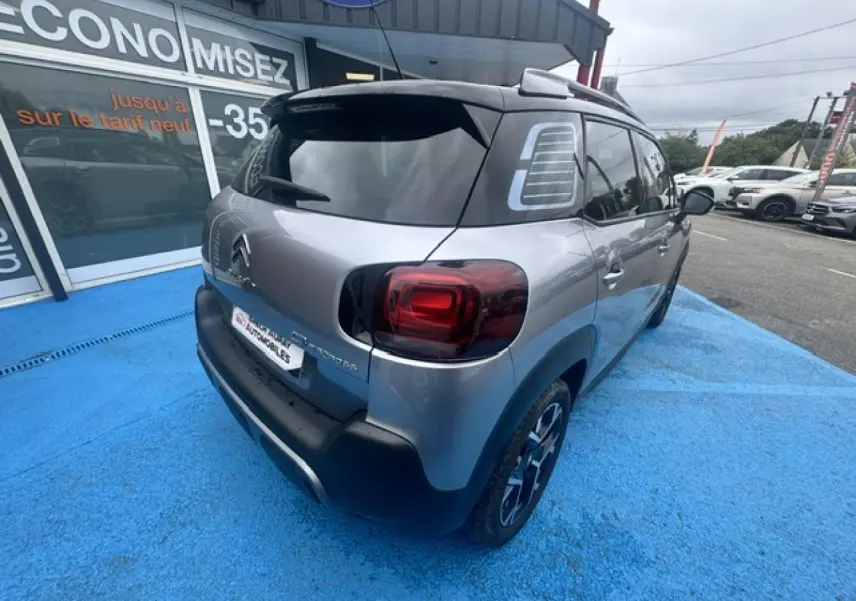 Vue 3/4 arrière droite d'un Citroën C3 Aircross gris acier avec toit noir et feux arrière distinctifs.