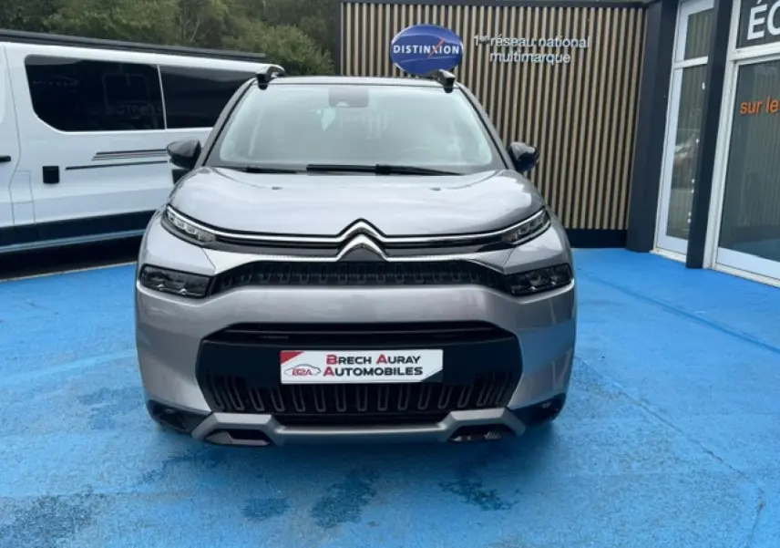 Vue avant d'un Citroën C3 Aircross gris acier 2024 avec calandre noire et barres de toit visibles.