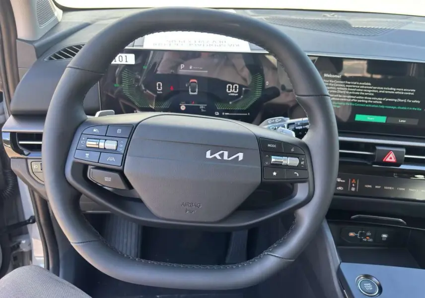 Vue intérieure centrée sur le volant cuir multifonctions noir du Kia Sportage 2026 avec tableau de bord digital et écran tactile.