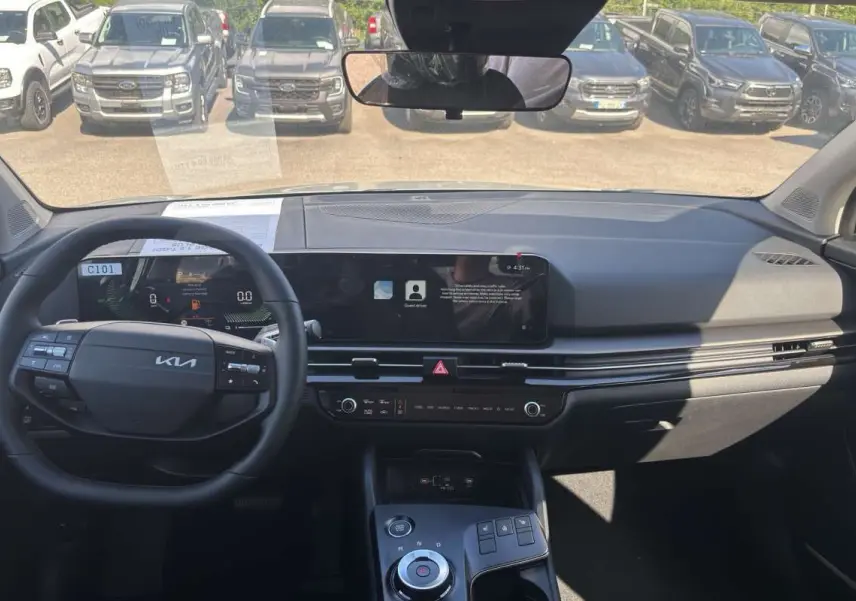 Vue intérieure avant du Kia Sportage gris céramique 2026, avec tableau de bord numérique et écran tactile large.