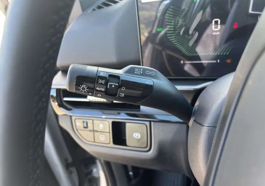 Gros plan sur la commande des feux et tableau de bord numérique du Kia Sportage gris céramique, version 2026.