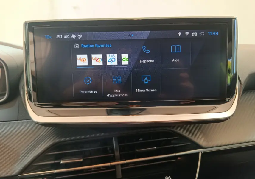 Écran tactile central de 10 pouces affichant les radios favorites dans l'habitacle du Peugeot 208 gris foncé.