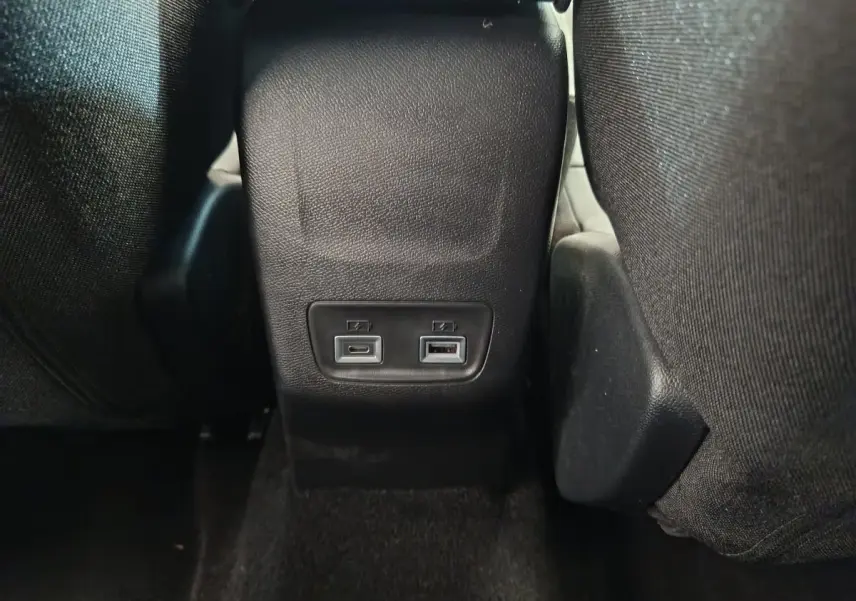 Prise USB type C et USB standard à l'arrière de la console centrale dans l'habitacle gris foncé d'une Peugeot 208 2025.