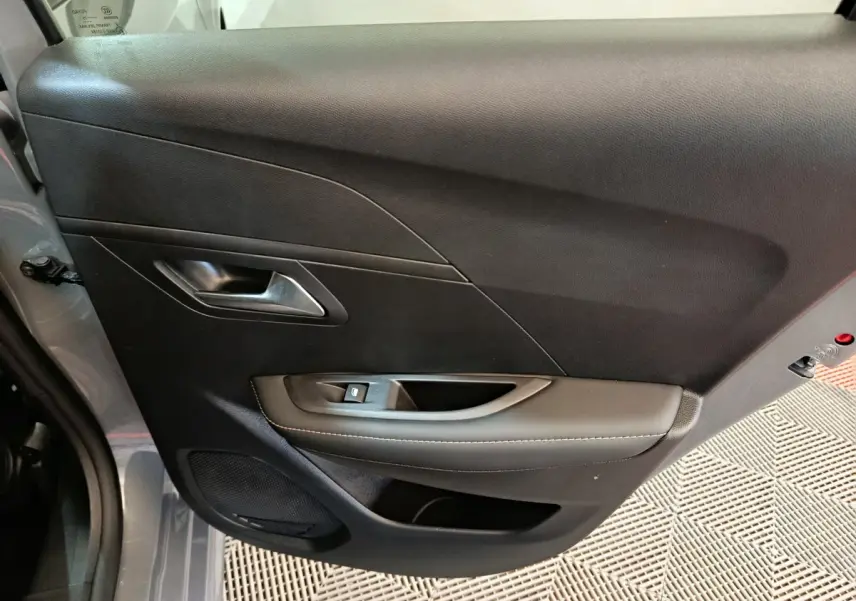 Vue intérieure côté gauche de la porte avant gris foncé de la Peugeot 208 PureTech 100 S&S Allure avec commande de vitre.