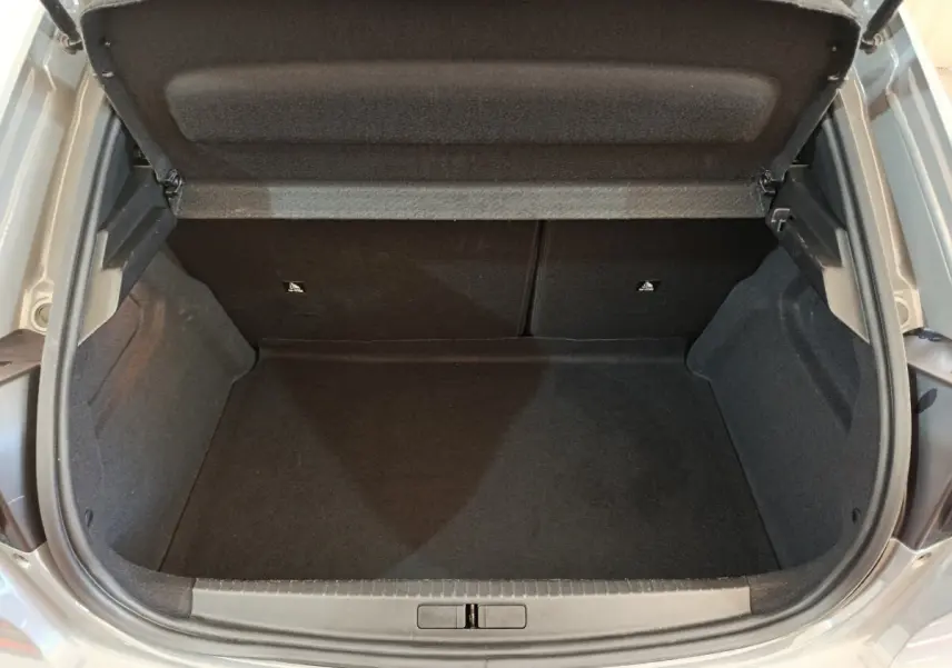 Coffre ouvert d'une Peugeot 208 gris foncé, vue de dessus montrant l'espace de chargement vide et propre.