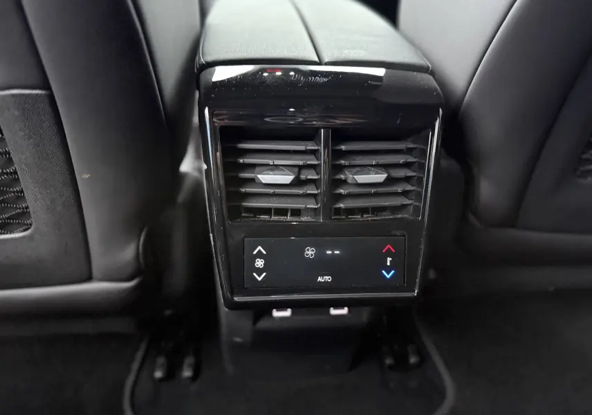 Vue rapprochée de la console arrière noire avec commandes de climatisation et aérateurs dans un DS7 Gris Titane 2025.