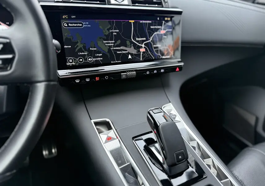 Vue intérieure centrée sur la console centrale et levier de vitesse de la DS7 2025 avec écran tactile de navigation allumé.