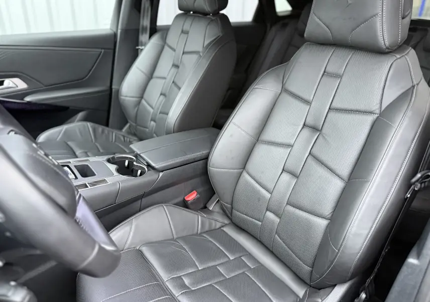 Vue intérieure rapprochée des sièges avant en cuir gris avec surpiqûres et logo DS embossé sur les appuie-têtes.