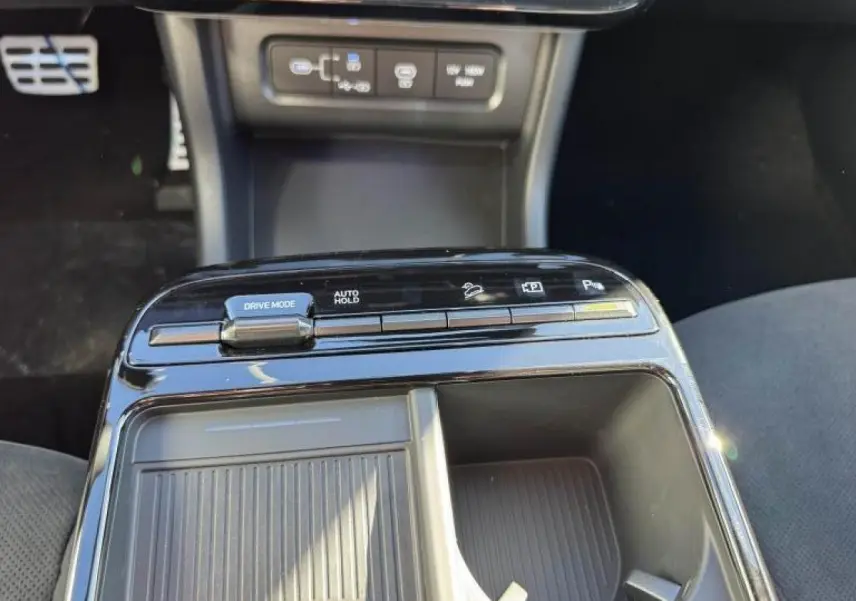 Gros plan sur la console centrale noire brillante du Hyundai Tucson 2025, avec commandes Drive Mode et Auto Hold visibles.