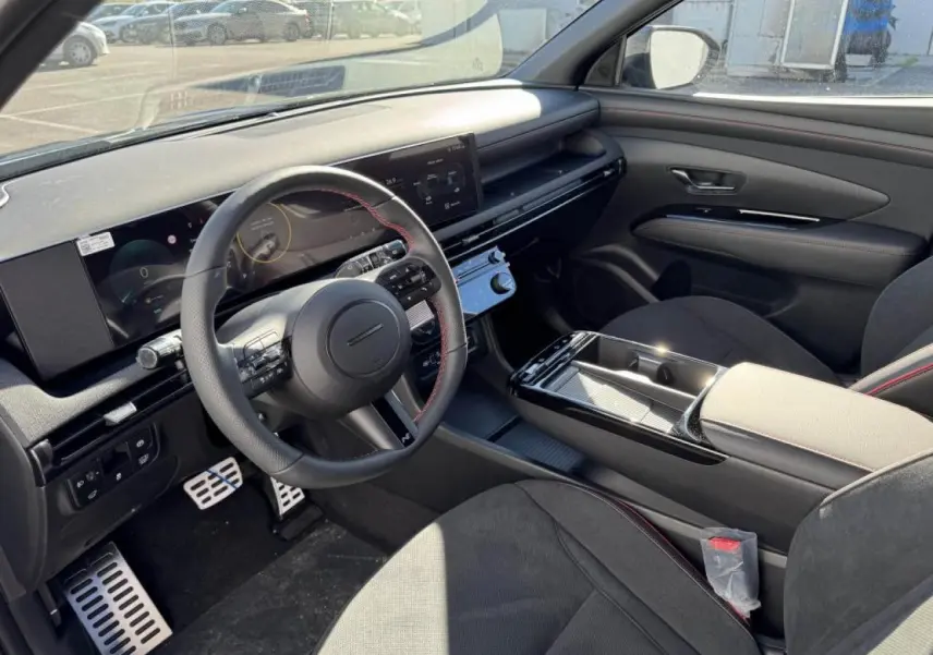 Vue intérieure côté conducteur du Hyundai Tucson 2025, avec volant cuir N Line à surpiqûres rouges et tableau de bord numérique.