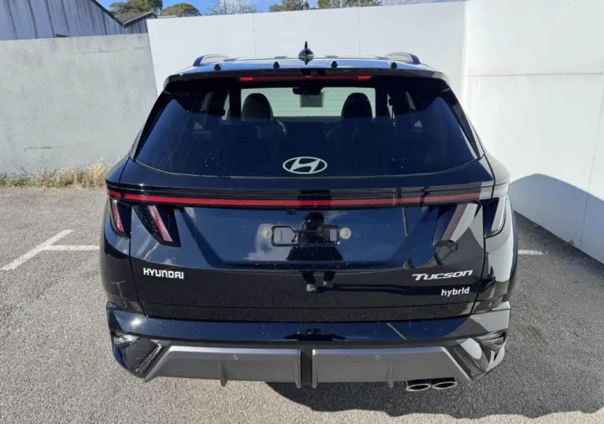 Vue arrière d'un Hyundai Tucson noir Abyss Metal avec feux LED reliés par un bandeau lumineux rouge.