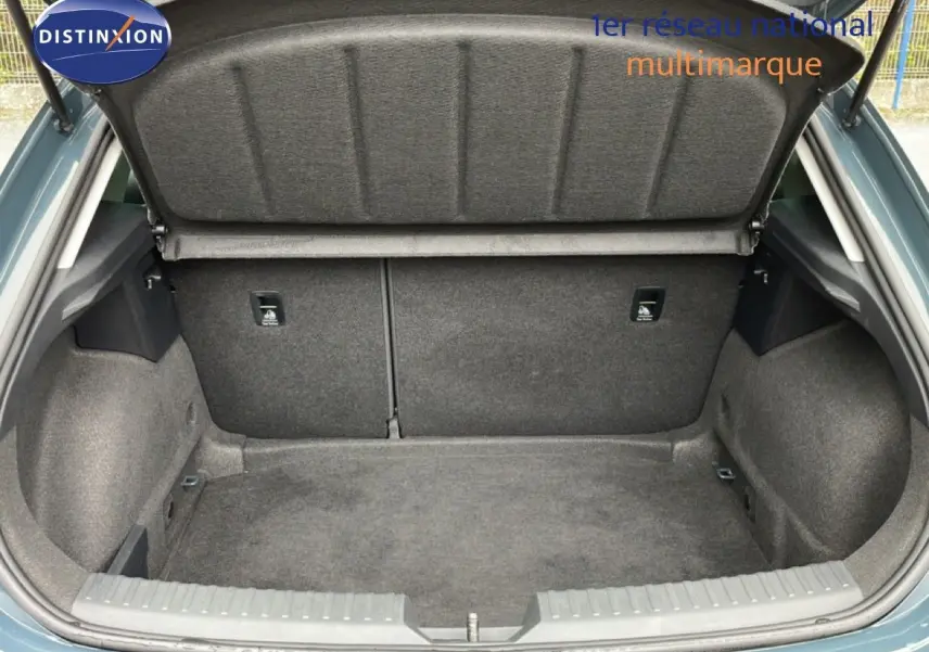 Coffre ouvert vu de l'arrière d'une SEAT LEON 2.0 TDI bleu fjord, montrant l'espace de rangement vide et la sellerie intérieure grise.
