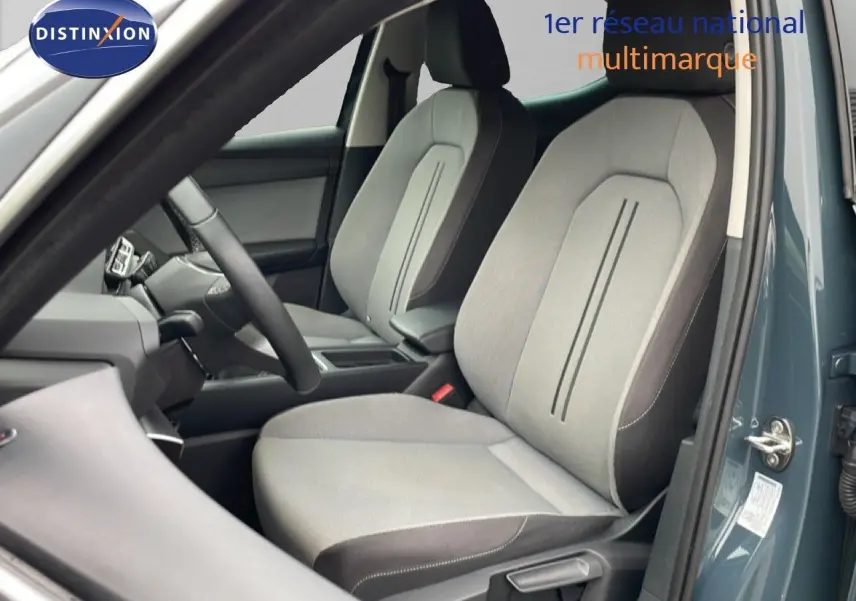 Vue intérieure côté conducteur du SEAT Leon 2025 bleu Fjord, mettant en valeur les sièges tissu gris clair avec contours foncés.