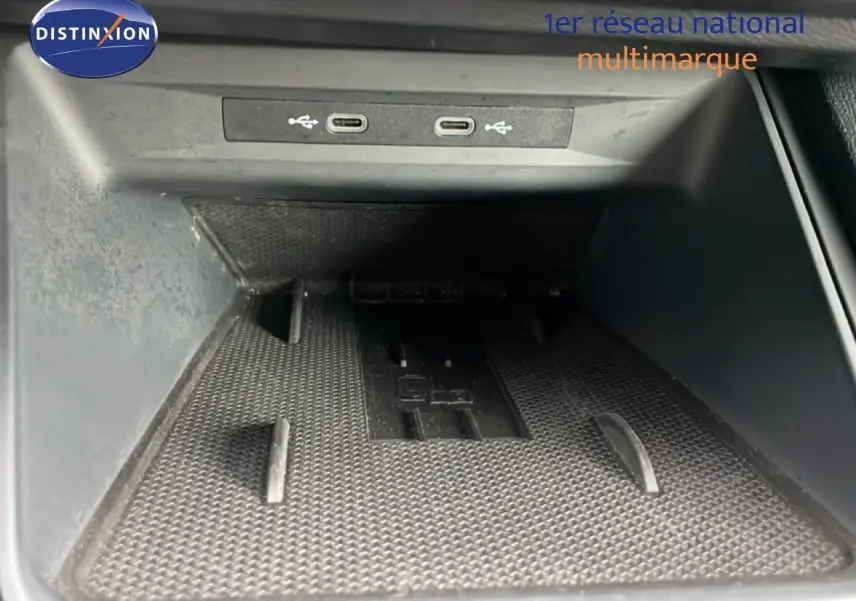 Gros plan sur la zone de rangement avant avec deux ports USB-C dans une SEAT LEON bleu Fjord 2025.