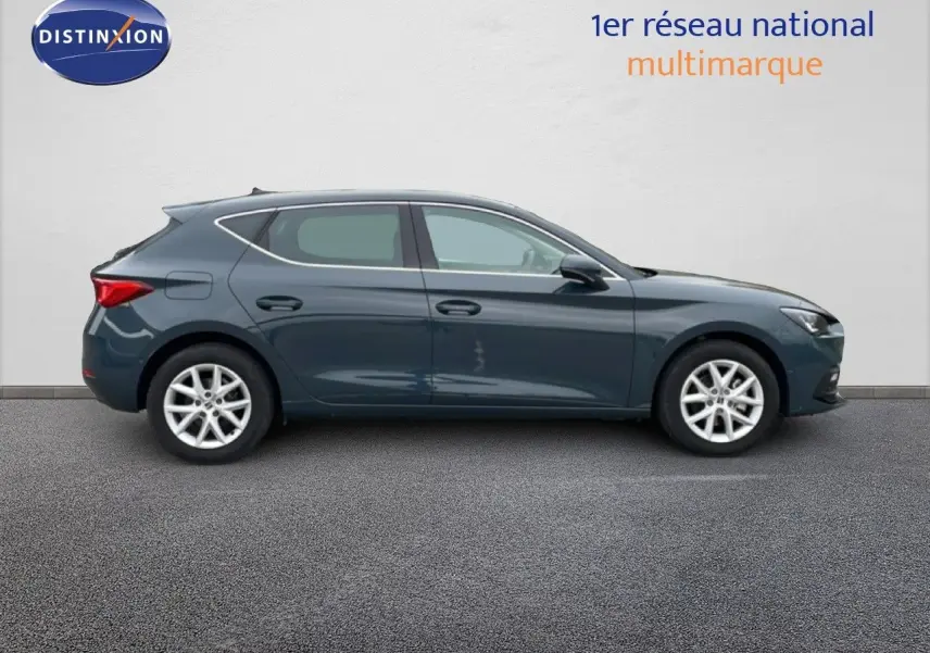 Vue latérale droite d'une SEAT LEON 2.0 TDI 115CH STYLE XL en bleu fjord, garée sur sol gris devant un mur clair.