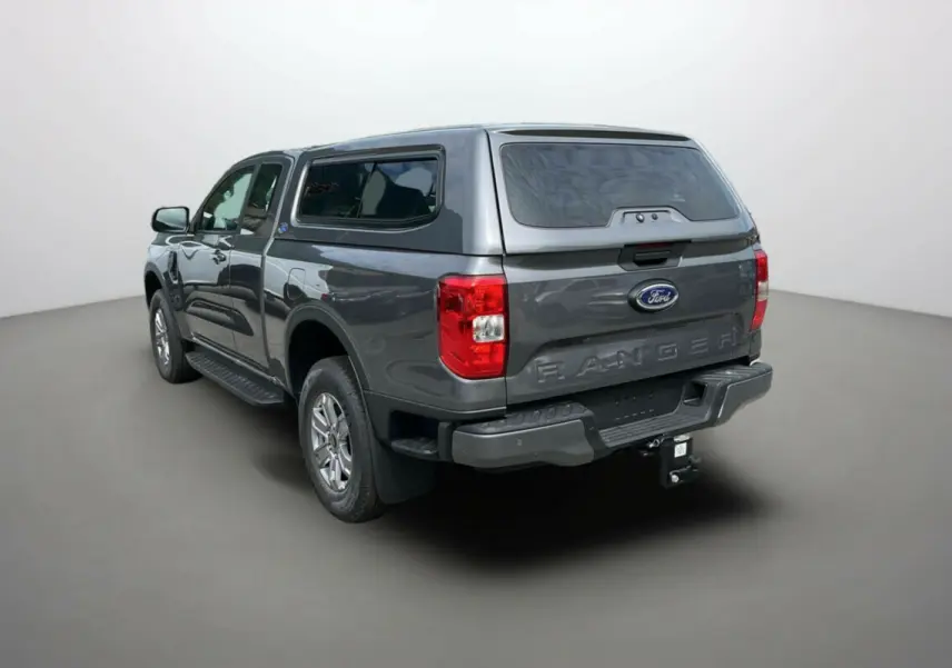 Ford Ranger gris carbone vu en 3/4 arrière droit avec hard-top et attelage visible.