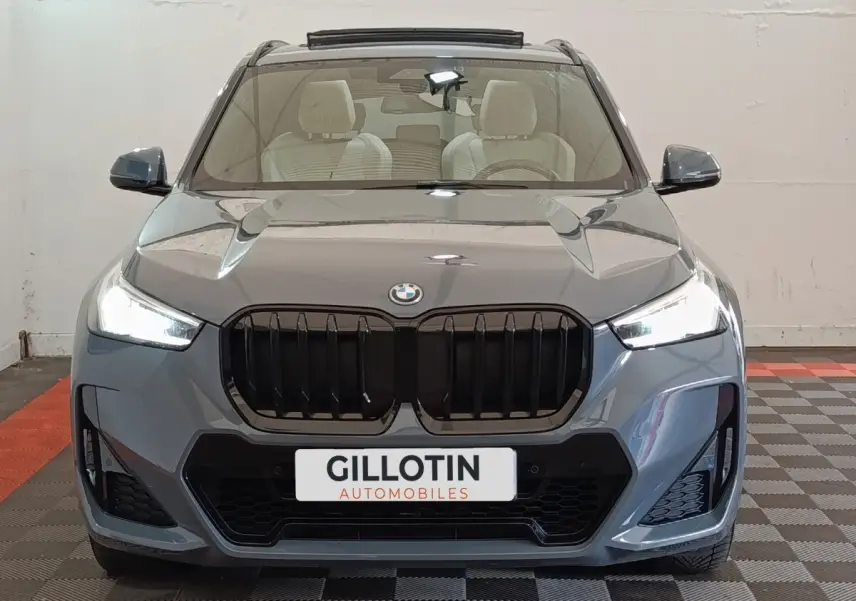 Vue frontale d'un BMW X1 xDrive25e M Sport gris foncé avec calandre noire et phares LED allumés.