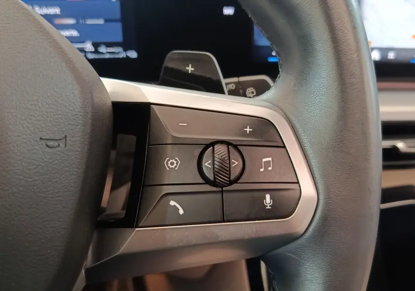 Gros plan sur les commandes multifonctions du volant cuir noir du BMW X1 xDrive25e M Sport 2024.