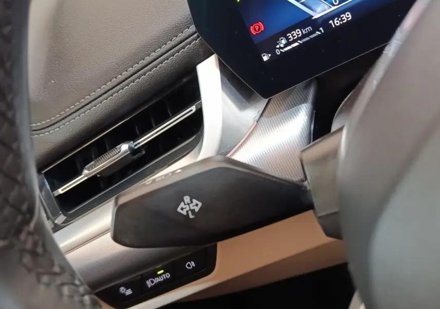 Détail intérieur du BMW X1 xDrive25e 2024 montrant le commodo de clignotant côté gauche et partie du tableau de bord gris foncé.