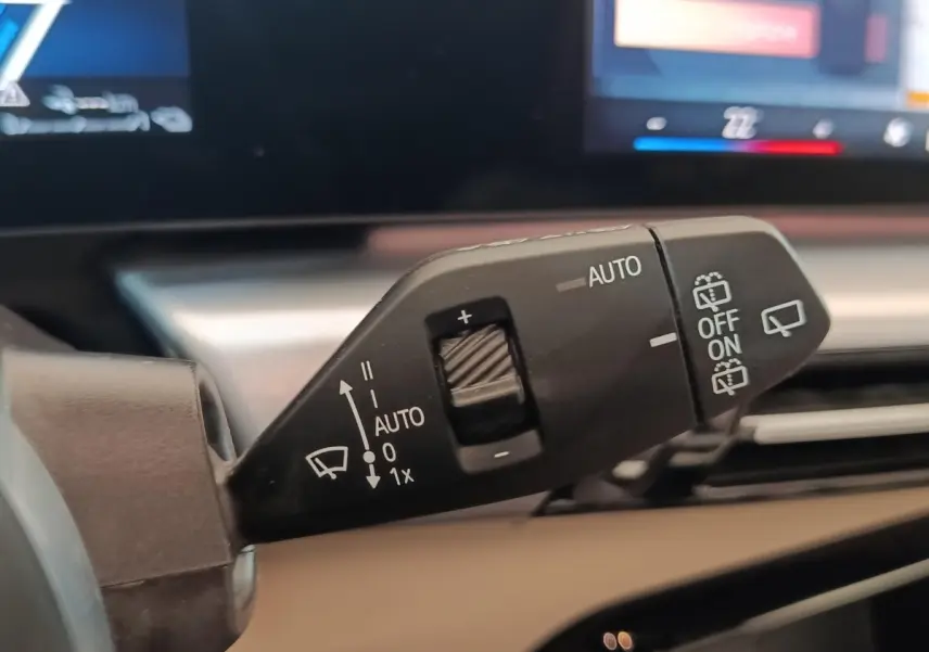 Gros plan sur la commande d’essuie-glace du BMW X1 xDrive25e M Sport gris foncé, avec affichage digital en arrière-plan.