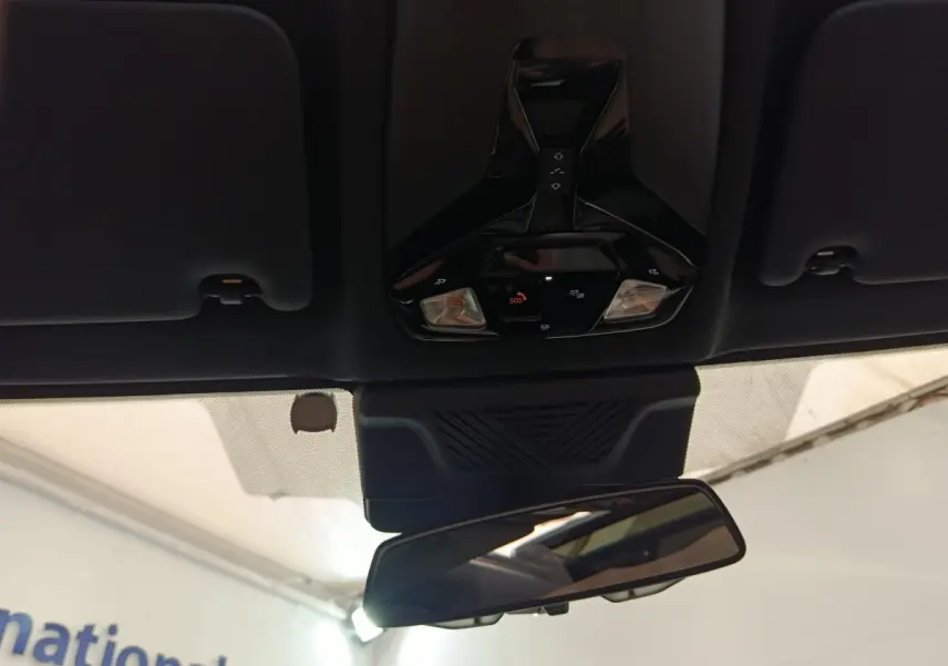 Vue intérieure centrée sur le plafonnier noir et le rétroviseur intérieur d'une BMW X1 gris foncé 2024.