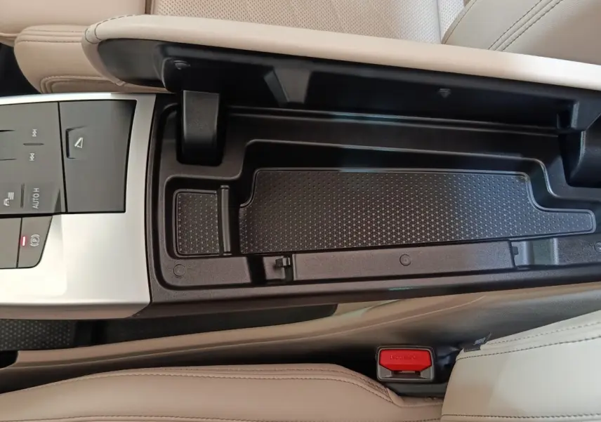 Vue rapprochée de la console centrale beige et noire du BMW X1 xDrive25e M Sport 2024 avec commandes et rangement ouvert.