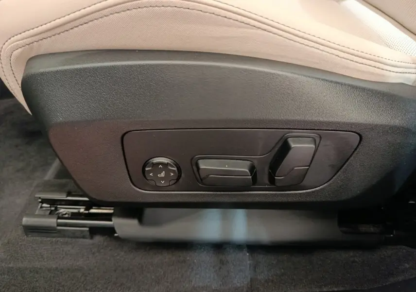 Détail des commandes électriques de réglage du siège avant beige dans un BMW X1 xDrive25e M Sport gris foncé 2024.