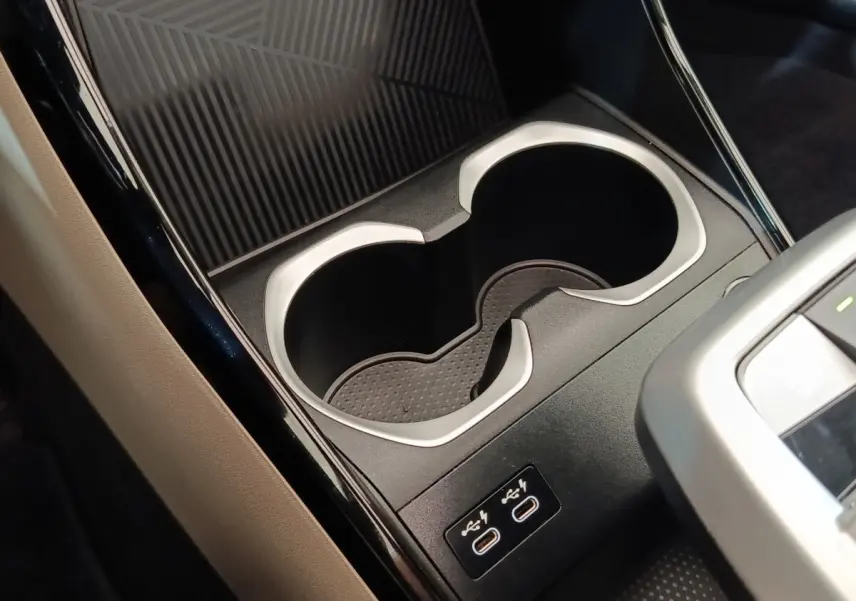 Gros plan intérieur sur les porte-gobelets et ports USB-C du BMW X1 xDrive25e M Sport gris foncé, côté console centrale.