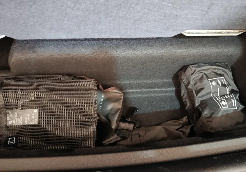 Compartiment de rangement sous plancher dans un BMW X1 xDrive25e M Sport gris foncé, avec trousse de secours et équipement.